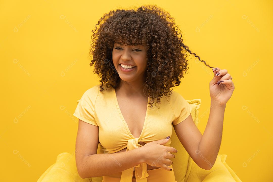 Feliz rindo mulher africana americana com seu cabelo encaracolado em fundo amarelo. Rindo