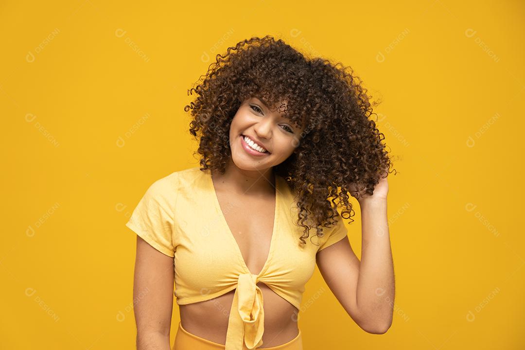 Feliz rindo mulher africana americana com seu cabelo encaracolado em fundo amarelo.