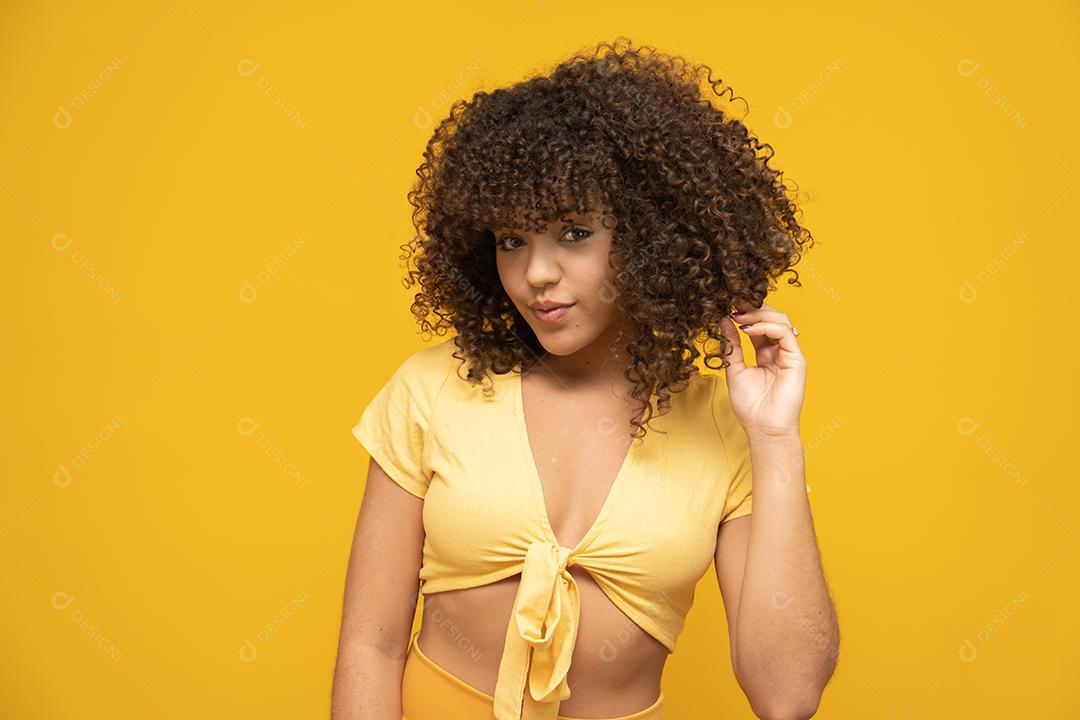 Feliz rindo mulher africana americana com seu cabelo encaracolado em fundo amarelo.