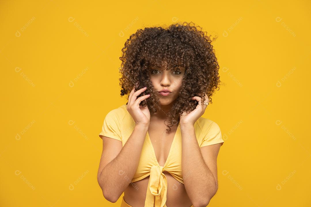 Feliz rindo mulher africana americana com seu cabelo encaracolado em fundo amarelo.