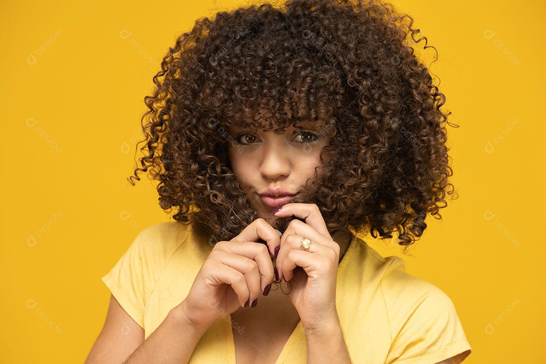 Feliz rindo mulher africana americana com seu cabelo encaracolado em fundo amarelo. Rindo