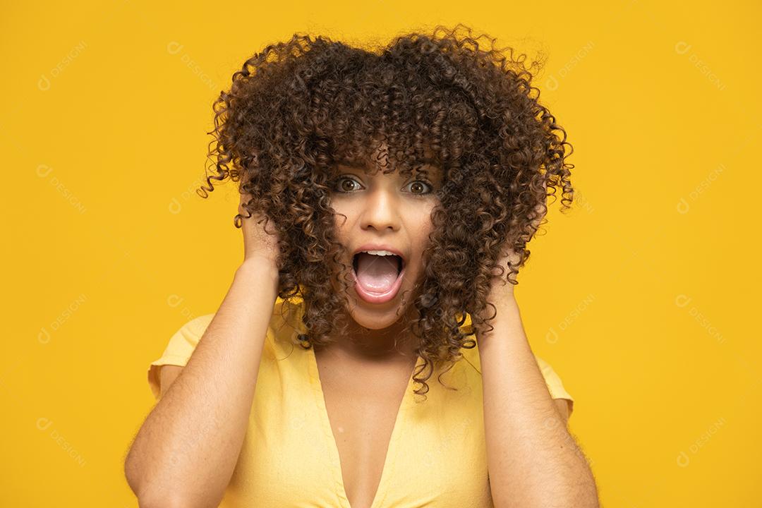 Feliz rindo mulher africana americana com seu cabelo encaracolado em fundo amarelo.