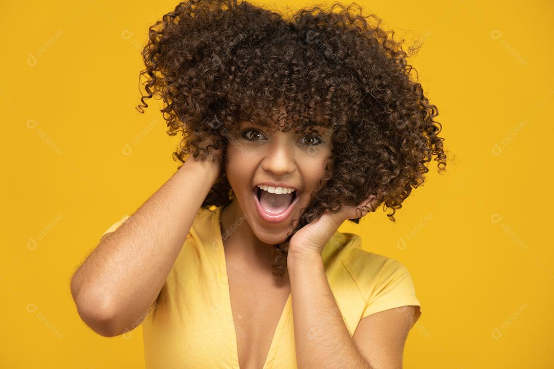 Feliz rindo mulher africana americana com seu cabelo encaracolado em fundo amarelo.