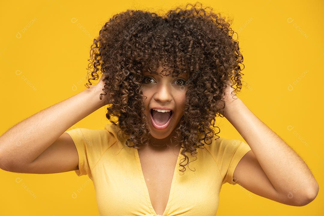 Feliz rindo mulher africana americana com seu cabelo encaracolado em fundo amarelo. Rindo
