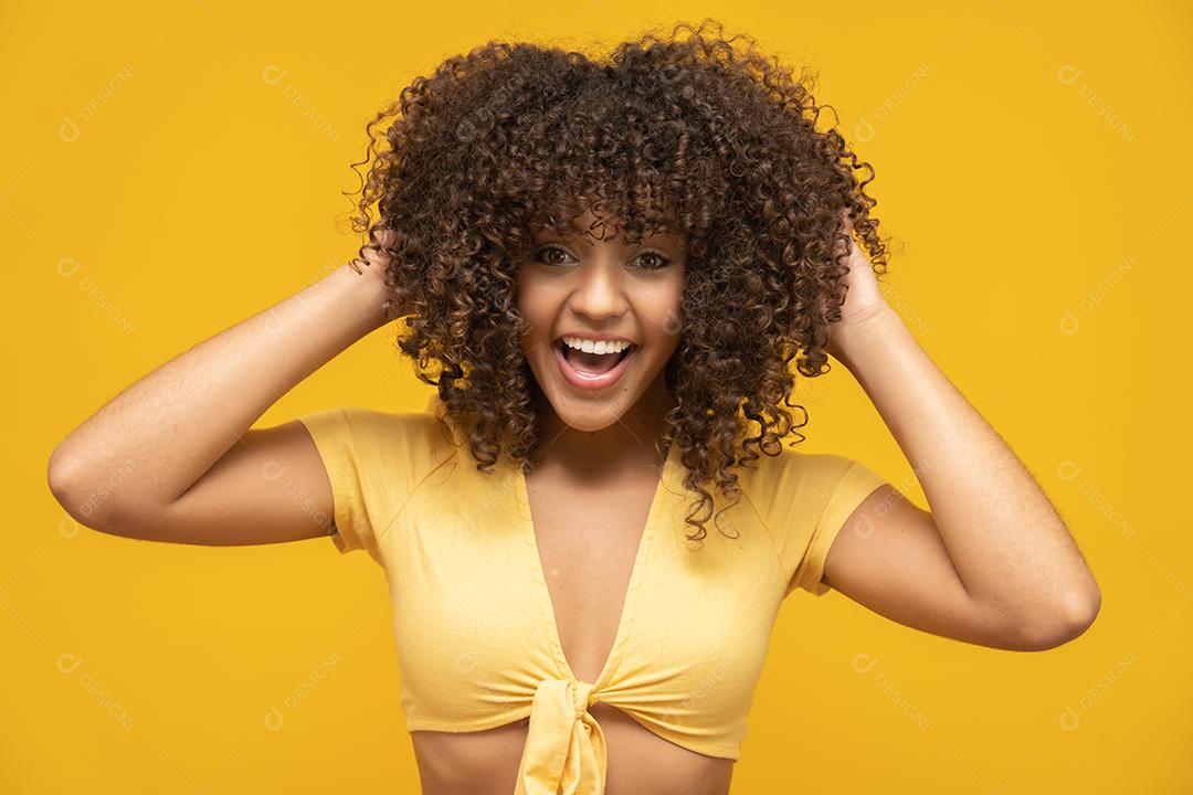 Feliz rindo mulher africana americana com seu cabelo encaracolado em fundo amarelo.