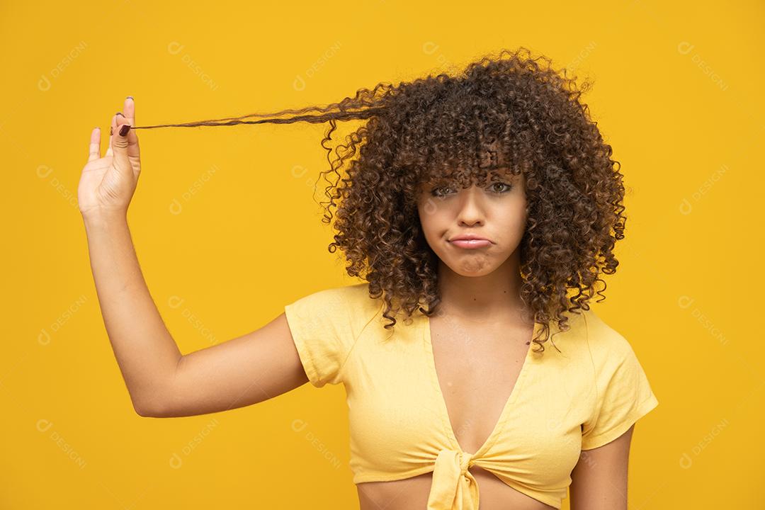 Happy laughing African American woman with her curly hair on yellow background.