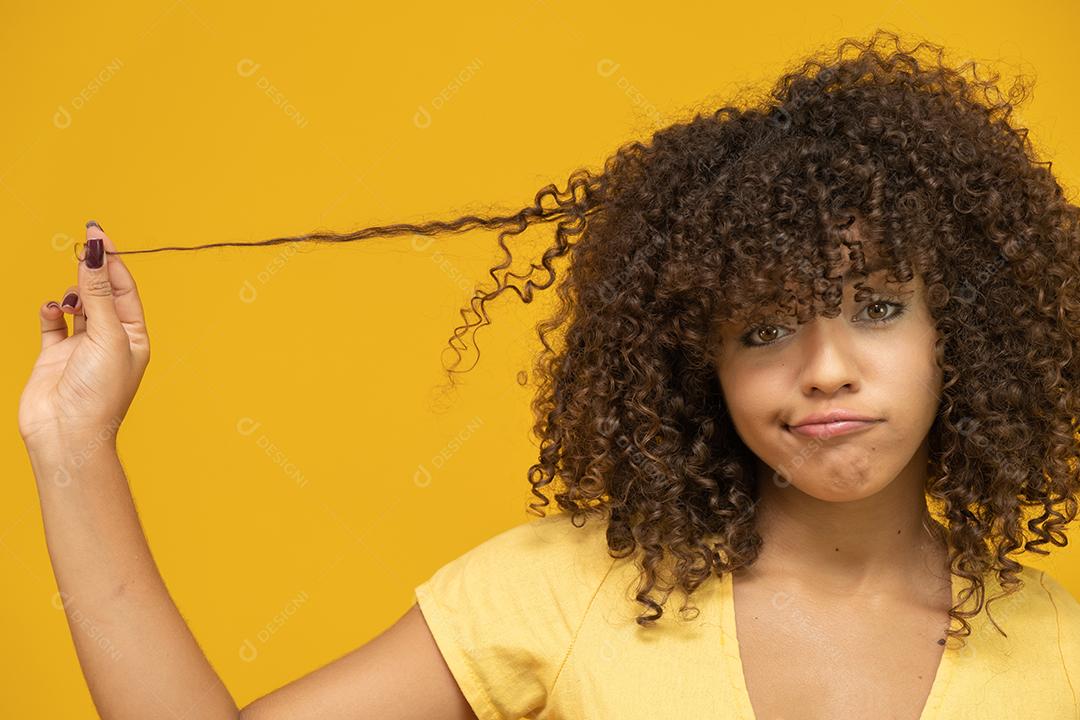 Feliz rindo mulher africana americana com seu cabelo encaracolado em fundo amarelo.