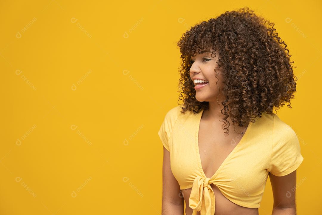 Feliz rindo mulher africana americana com seu cabelo encaracolado em fundo amarelo.