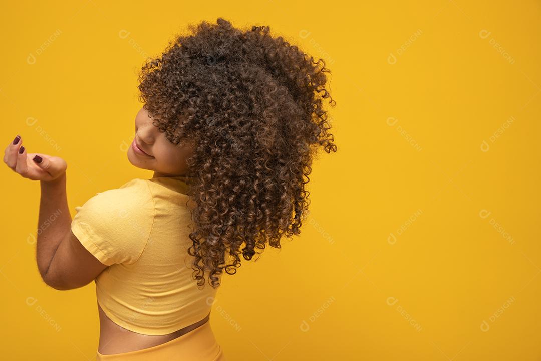Mulher africana americana para trás com seu cabelo encaracolado em fundo amarelo. Rindo mulher