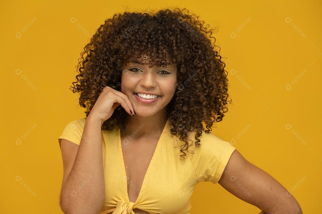 Mulher afro-americana com penteado afro e maquiagem glamourosa. Fundo amarelo.