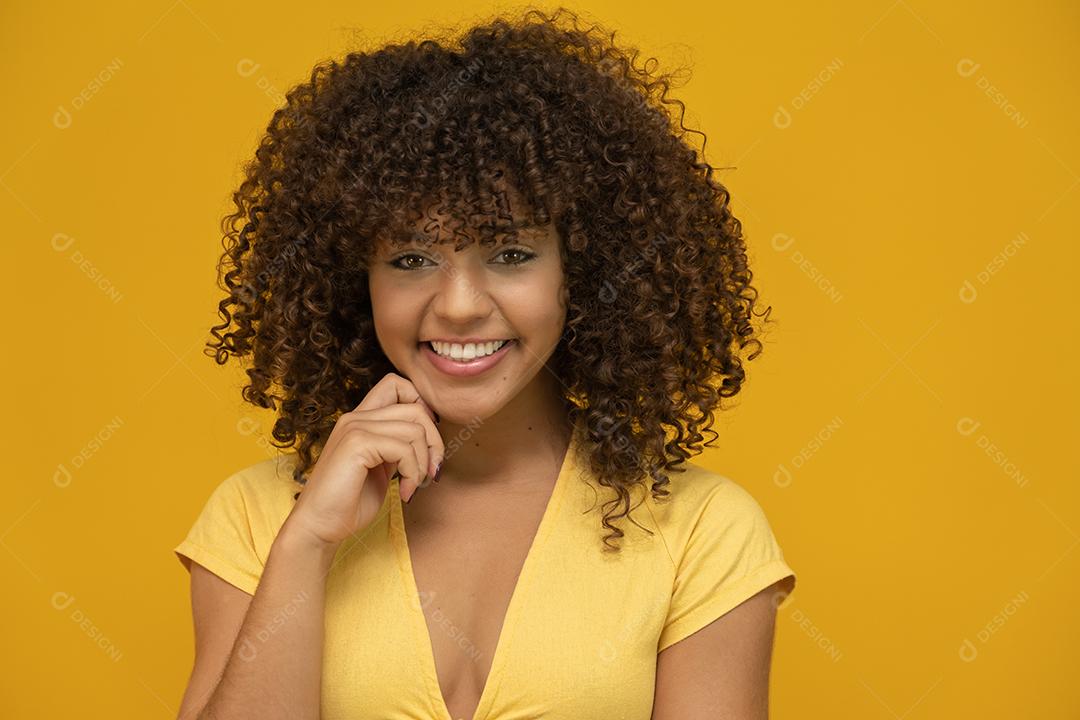 Mulher afro-americana com penteado afro e maquiagem glamourosa. Fundo amarelo.