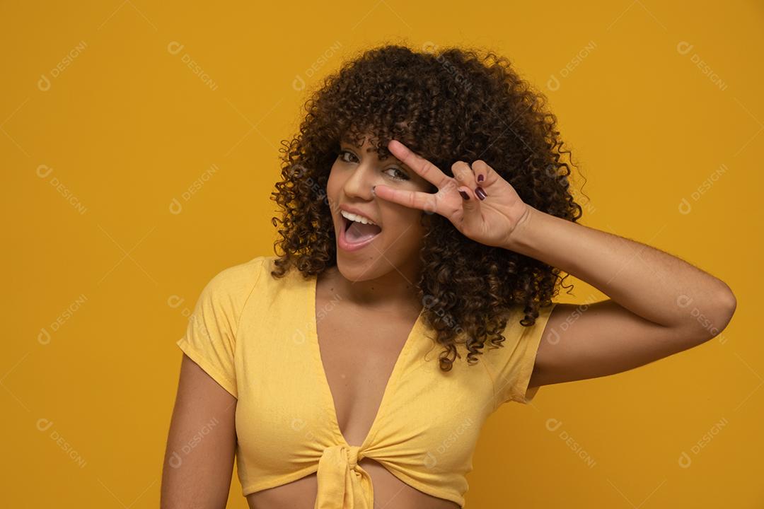 Mulher africana americana para trás com seu cabelo encaracolado em fundo amarelo.