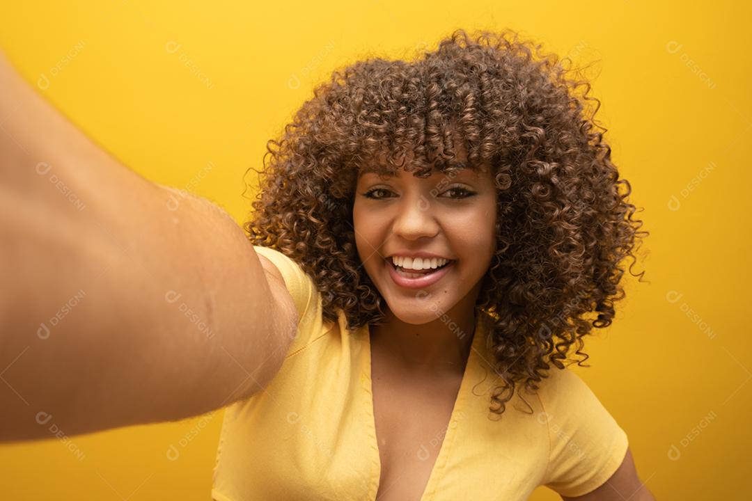 Feche de animada jovem afro-americana em suéter de pele posando isolado em fundo amarelo