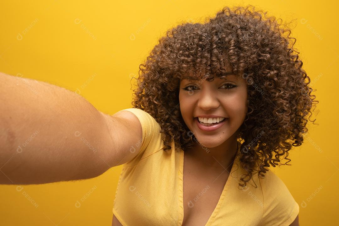 Feche de animada jovem afro-americana em suéter de pele posando isolado em fundo amarelo