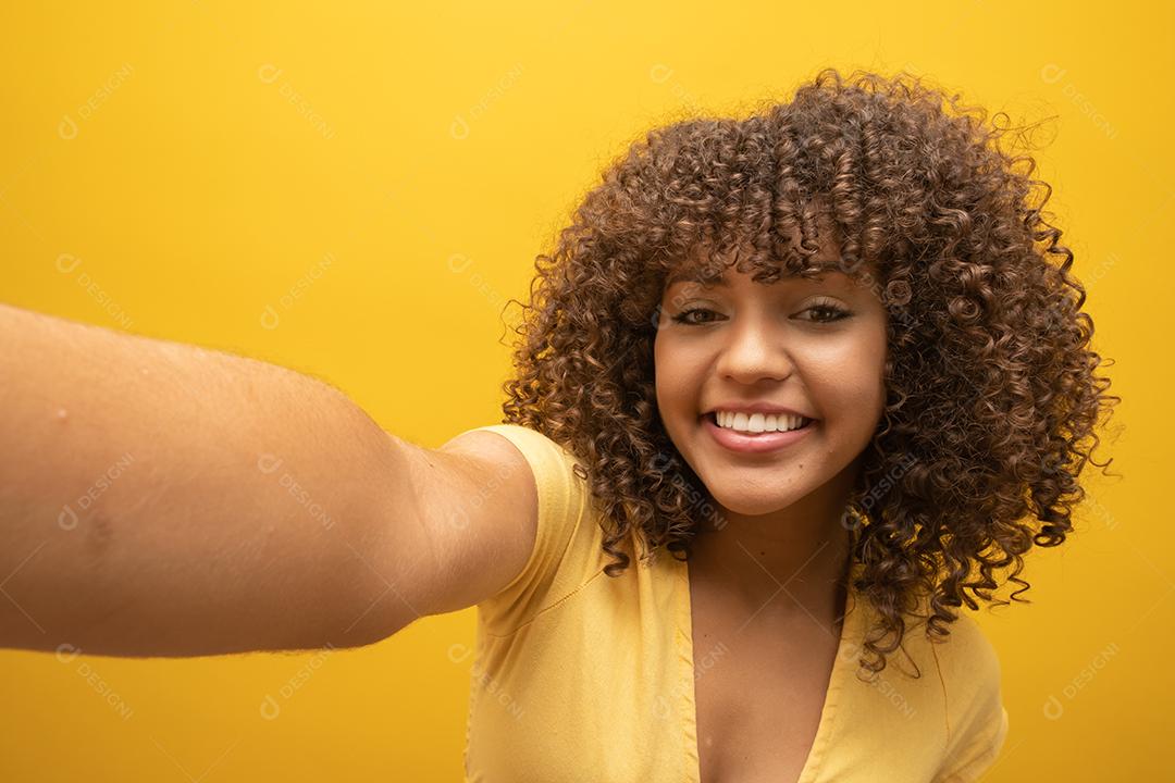 Close up of excited young African American woman in fur sweater posing isolated on yellow background