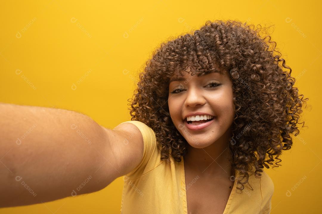 Feche de animada jovem afro-americana em suéter de pele posando isolado em fundo amarelo