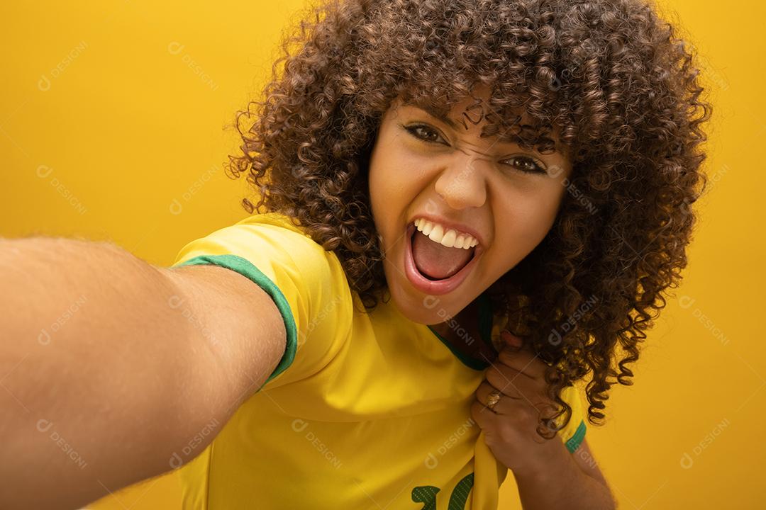 Torcedor do Brasil. Fã de mulher brasileira comemorando na partida de futebol em fundo amarelo