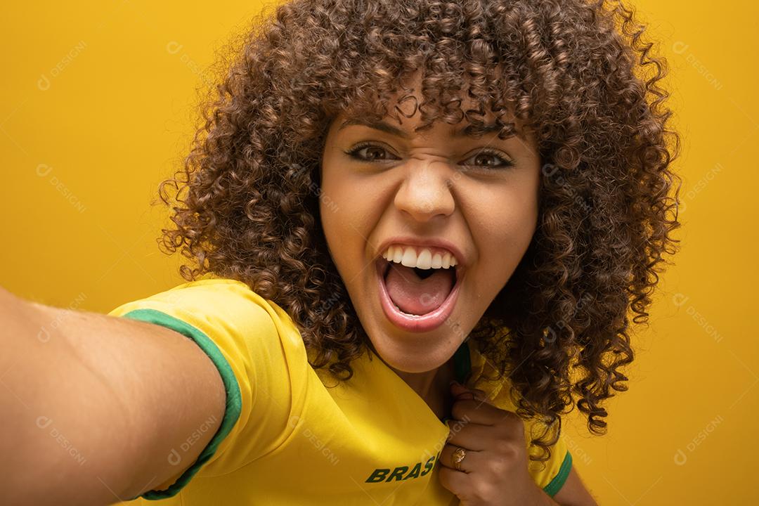 Torcedor do Brasil. Fã de mulher brasileira comemorando na partida de futebol em fundo amarelo