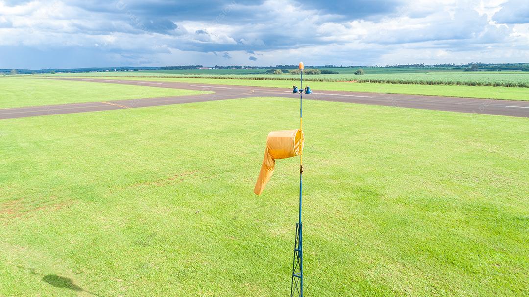 Meia de vento laranja no aeródromo, fundo de plantação de cana-de-açúcar.