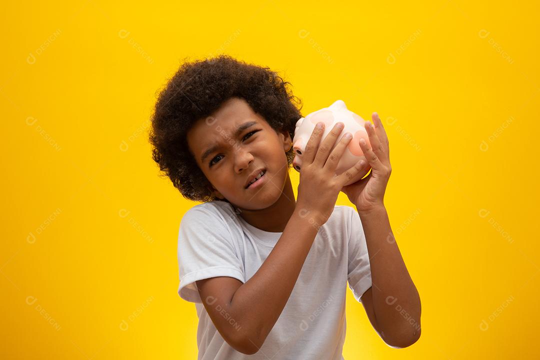 Garoto negro coletando dinheiro para o cofrinho. Garotinho colocando dinheiro no cofrinho