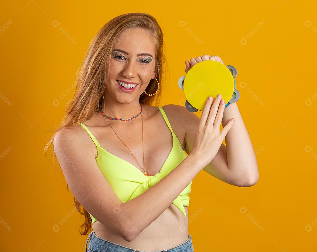 Mulher loira de cabelo comprido com um pandeiro de brinquedo nas mãos