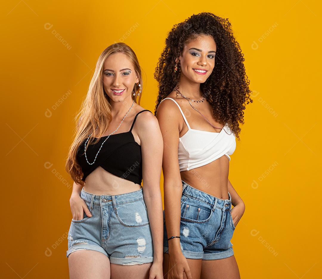 Mulheres loiras e morenas se divertindo retrato contra amarelo