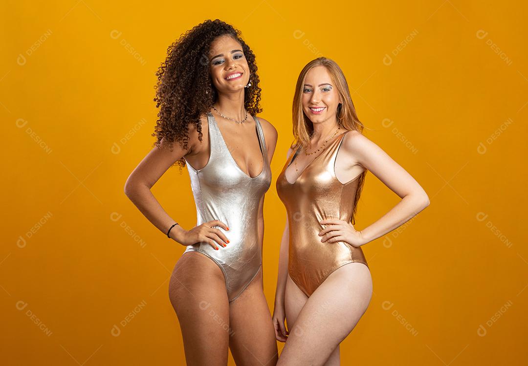 Mulheres loiras e morenas se divertindo retrato contra amarelo