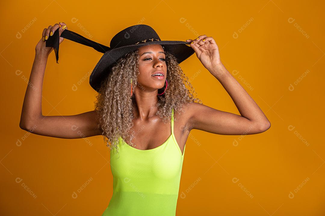 Garota de cabelo encaracolado atraente em um maiô de praia verde brilhante, chapéu, boca aberta