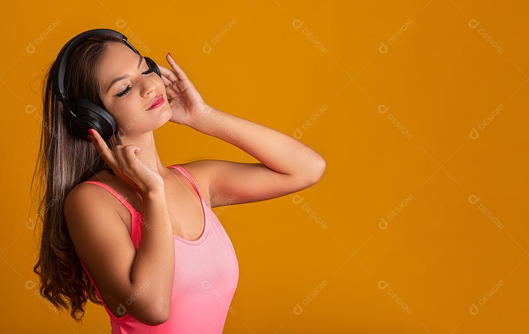 Garota atraente com fones de ouvido em um fundo amarelo brilhante. Conceito de DJ.