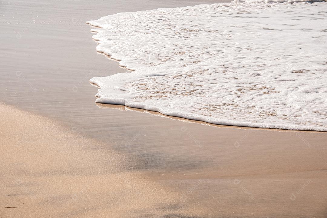 Ondas suaves com espuma do oceano no fundo da praia