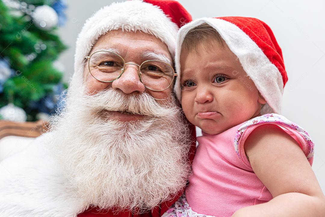 Bebezinho com medo de Papai Noel. Chorando assustado com a grande barba branca.