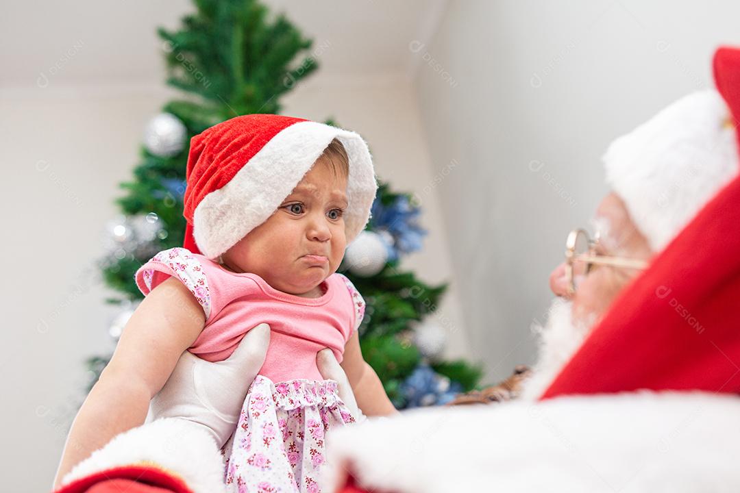 Bebezinho com medo de Papai Noel. Chorando assustado com a grande barba branca.