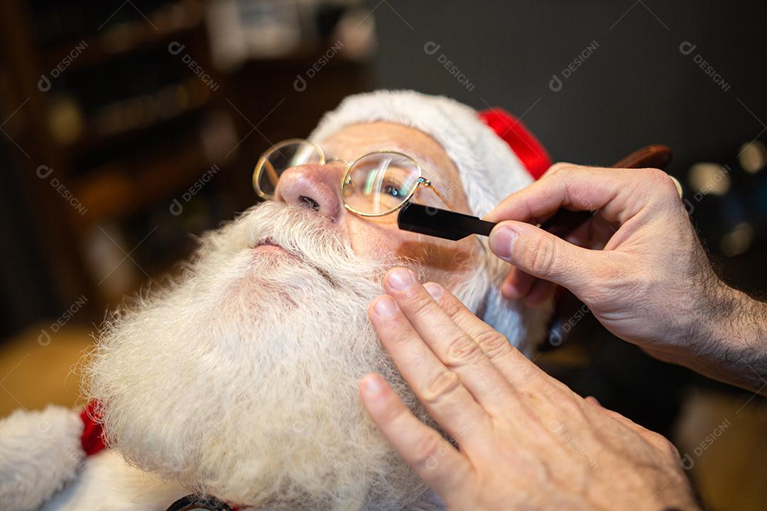 Papai Noel se barbeando na barbearia. Olhando no espelho