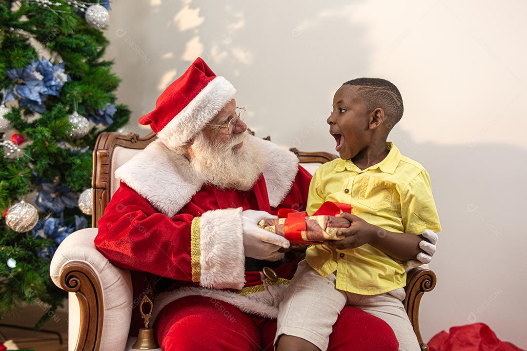 Papai Noel entregando uma caixa de presente para um menino africano