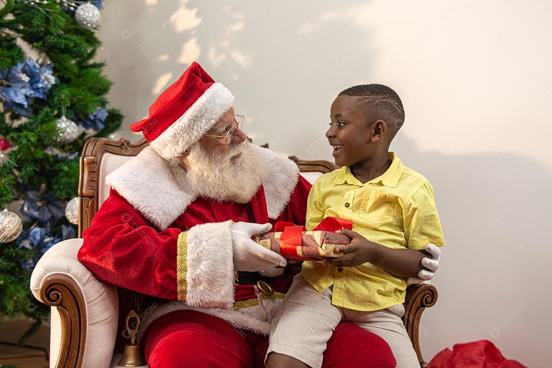 Papai Noel entregando uma caixa de presente para um menino africano