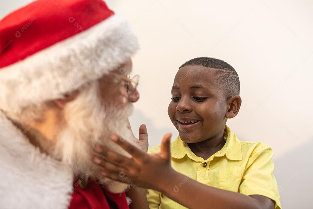 Papai Noel entregando uma caixa de presente para um menino africano