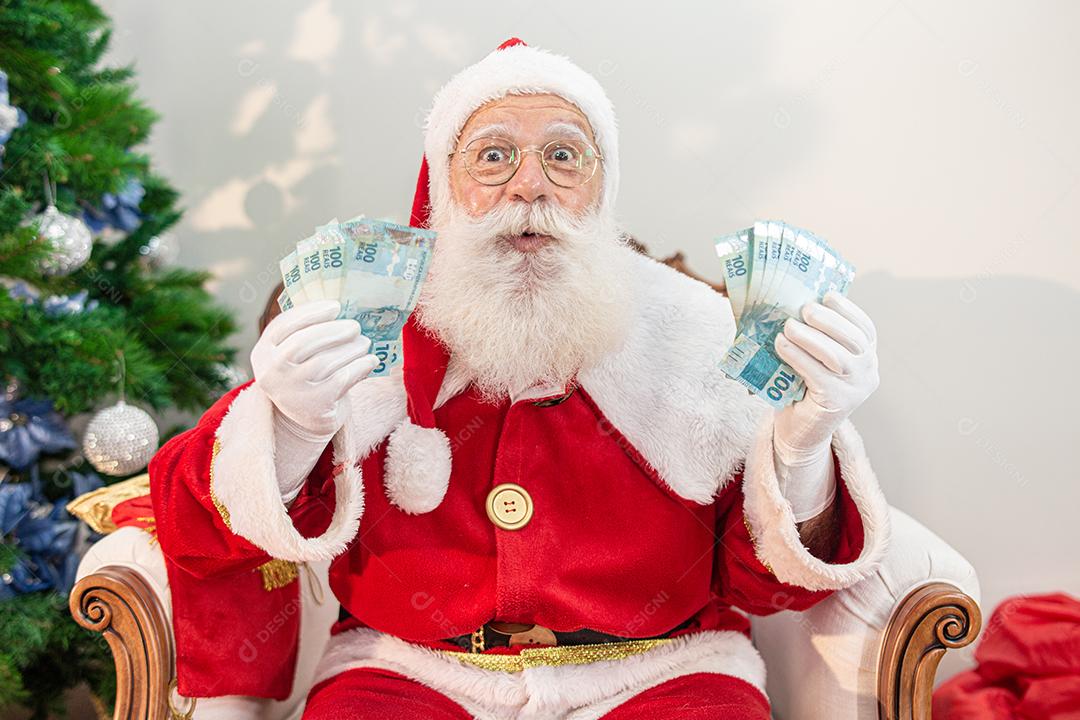 Papai Noel contando contas de dinheiro brasileiras. Notas reais. 100 Reais
