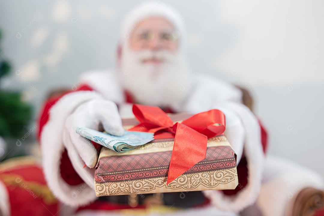 Papai Noel oferecendo um presente e dinheiro para a câmera. Recebimento