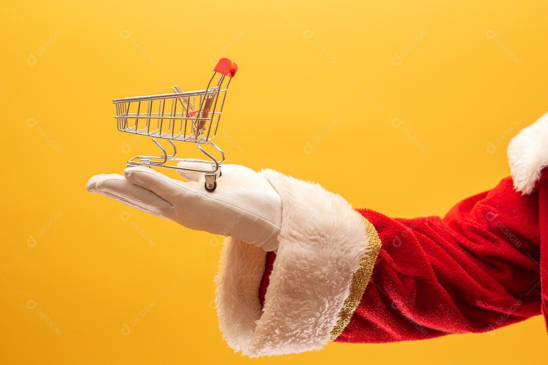 Papai Noel e o supermercado, ele está mostrando um mini carrinho
