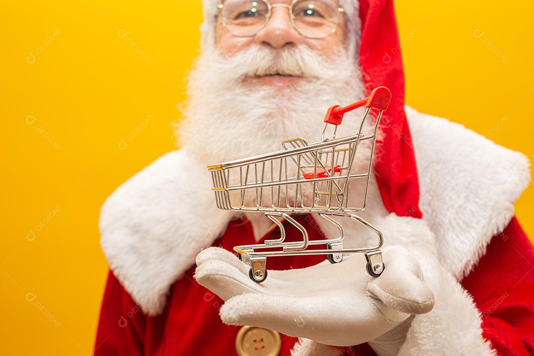 Papai Noel e o supermercado, ele está mostrando um mini carrinho