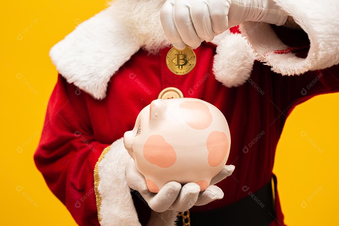 Papai Noel colocando moeda em um cofrinho de cerâmica. Poupança