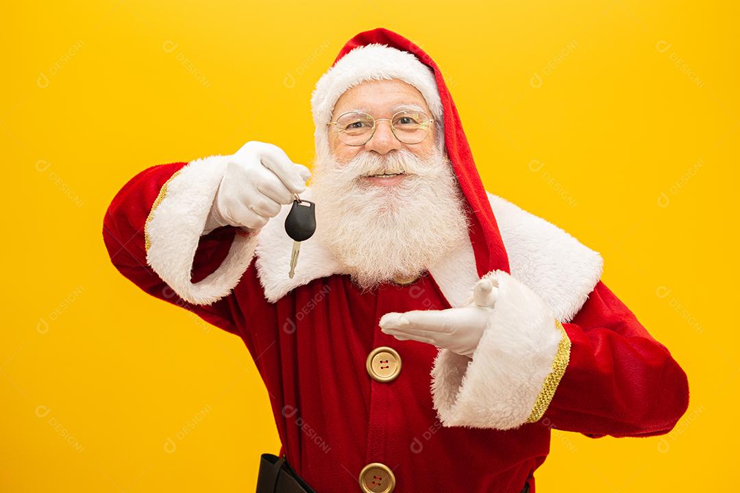 Papai Noel segurando chaves de um carro em fundo amarelo