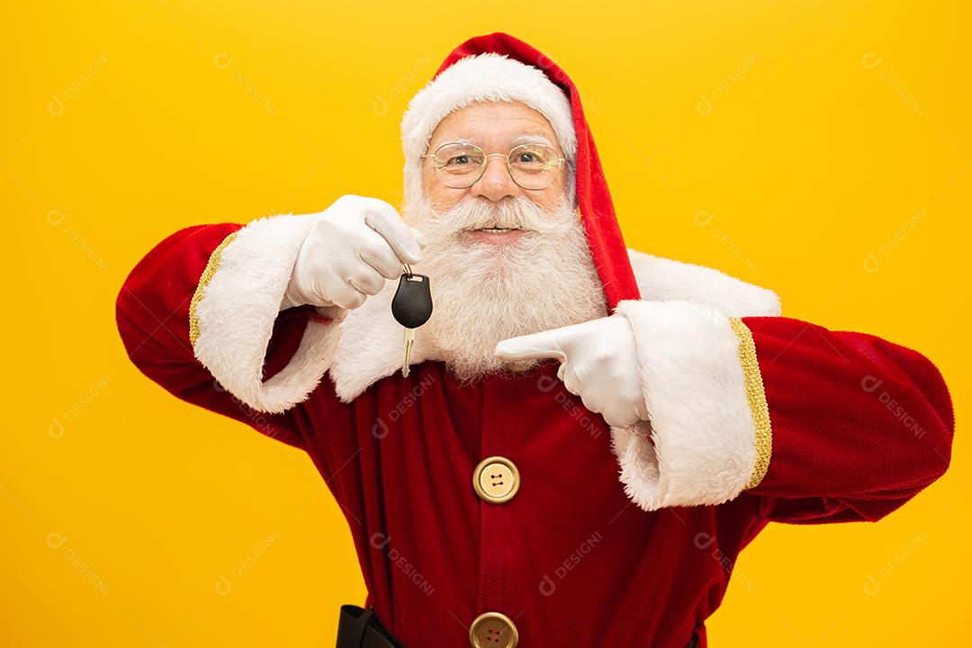 Papai Noel segurando as chaves de um carro em fundo amarelo.