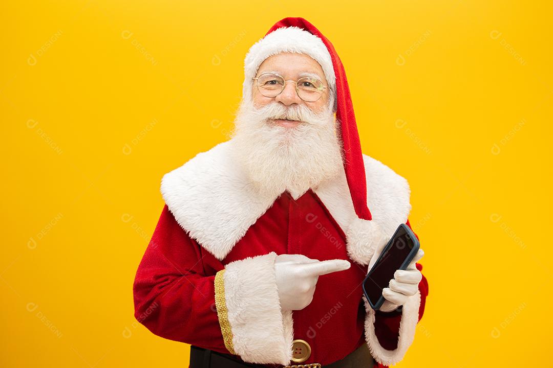 Papai Noel com celular no fundo amarelo. Conceito de comunicador