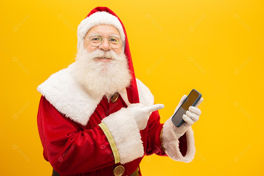 Papai Noel com celular no fundo amarelo. Conceito de comunicador