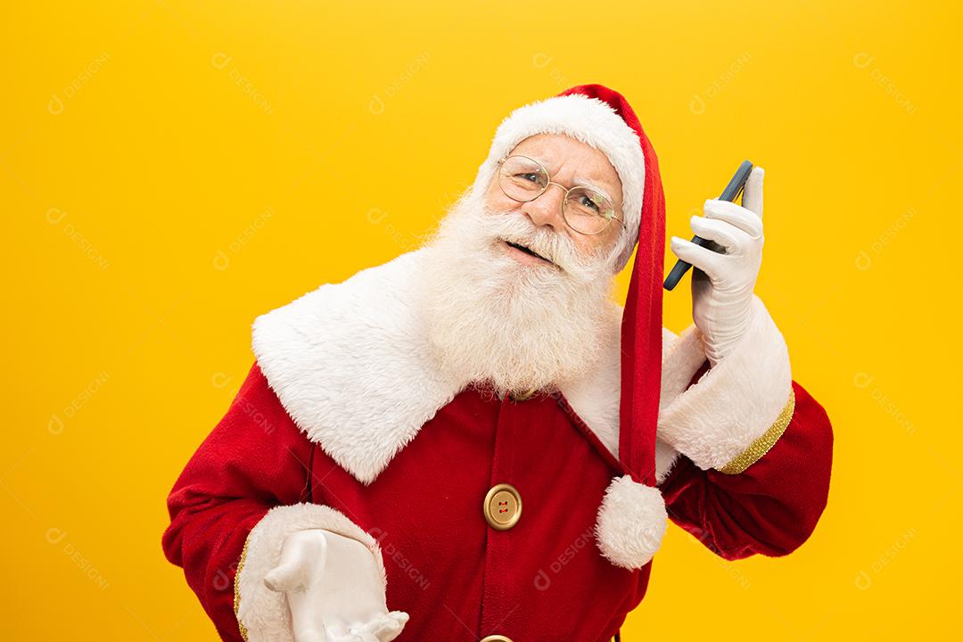 Papai Noel com celular no fundo amarelo. Conceito de comunicador