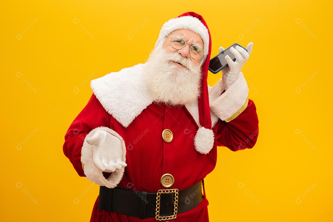 Papai Noel com celular no fundo amarelo. Conceito de comunicador