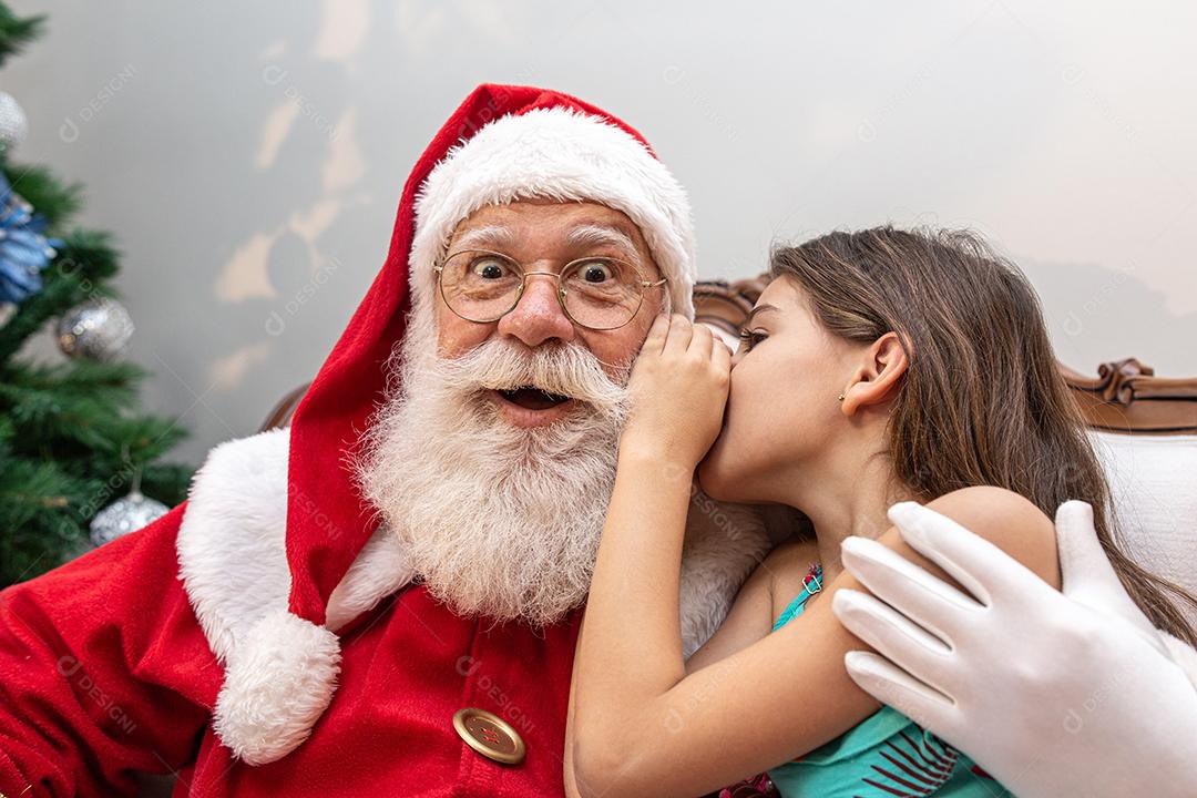 Menina sussurrando no ouvido do Papai Noel. Contando um segredo. Revelar