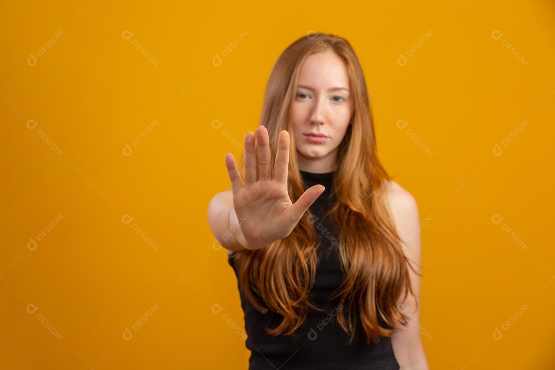 Bela mulher ruiva de pé sobre fundo amarelo isolado