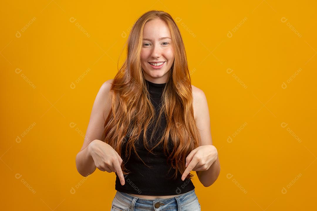 Uma garota ruiva em fundo de estúdio amarelo oferece oportunidades